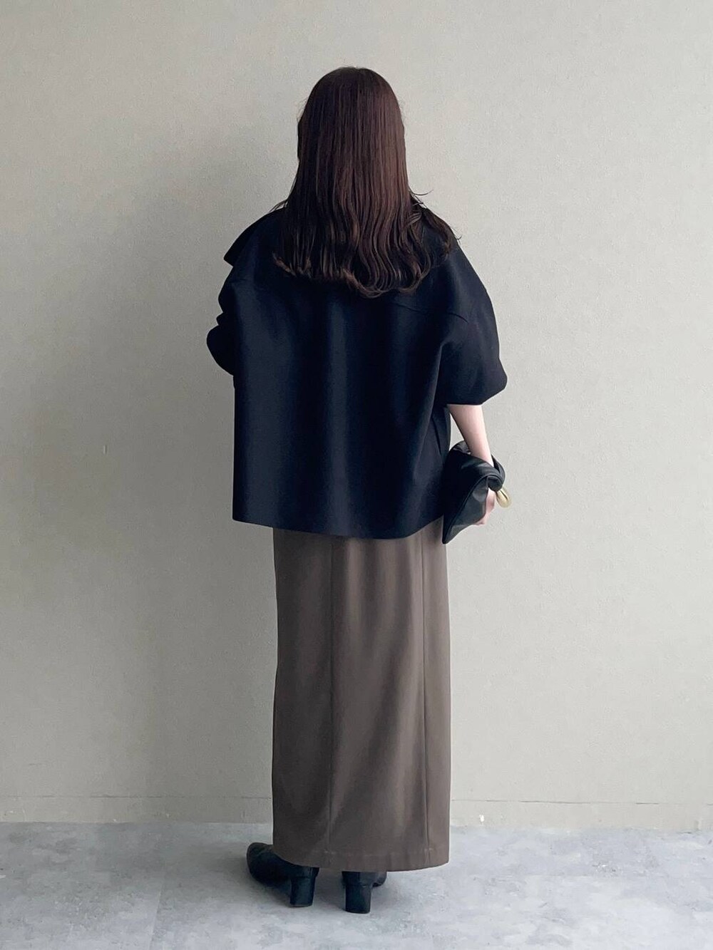 ブラック系のピーコート、ブラック系のハンドバッグ、ブラック系のブーツを着用したレディースの秋コーディネートの2枚目の写真