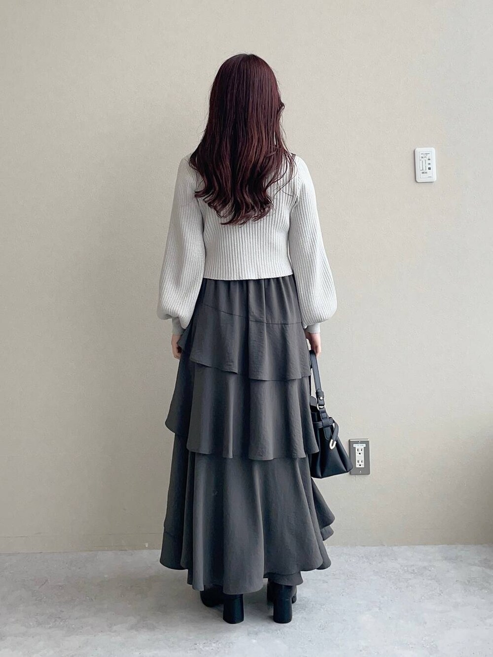 ブラック系のショルダーバッグ、ブラック系のブーツ、グレー系のカーディガン/ボレロを着用したレディースの秋コーディネートの2枚目の写真