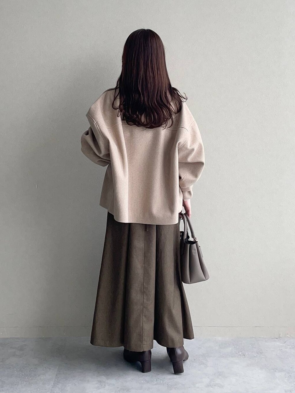 ホワイト系のピーコート、ベージュ系のショルダーバッグ、ブラウン系のワンピースを着用したレディースの秋コーディネートの2枚目の写真