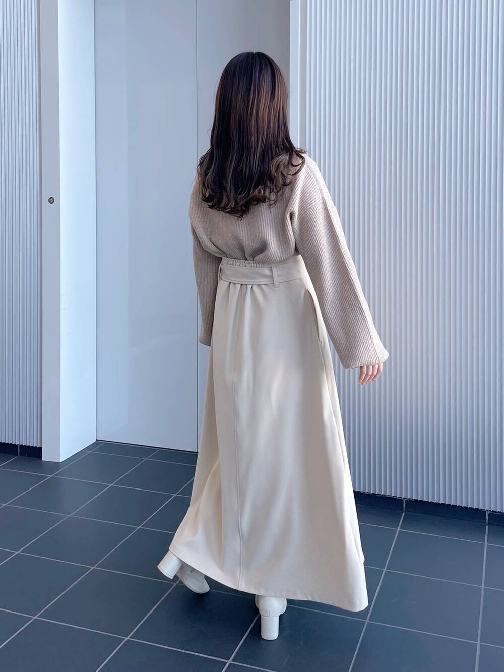 ベージュ系のニット/セーター、ホワイト系のブーツ、ベージュ系のジャンパースカートを着用したレディースの冬コーディネートの2枚目の写真