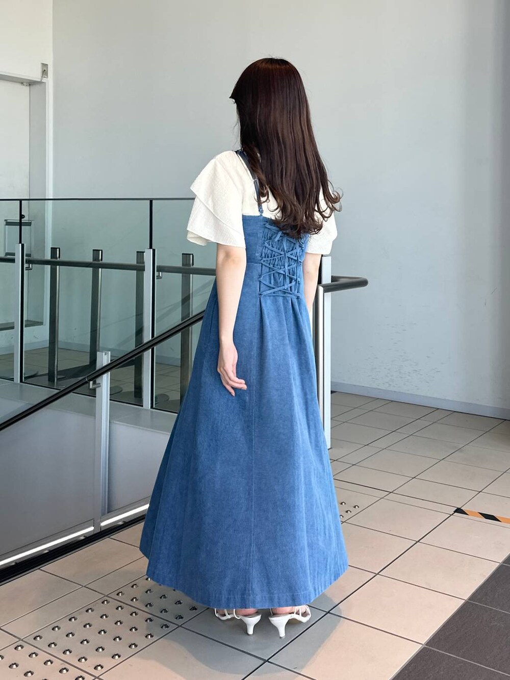 ブルー系のジャンパースカート、ホワイト系のサンダル、ホワイト系のTシャツ/カットソーを着用したレディースの夏コーディネートの2枚目の写真