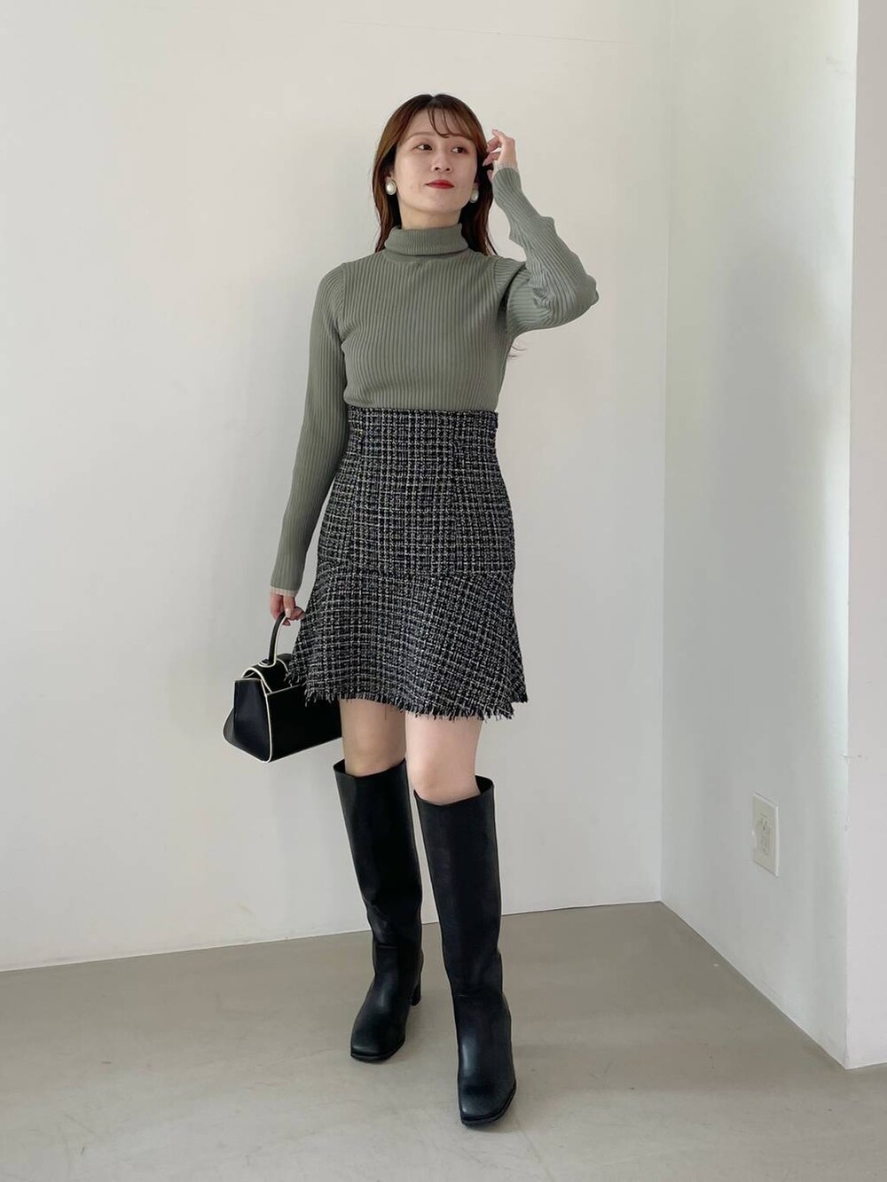 ブラック系のハンドバッグ、ブラック系のブーツ、ブラック系のノーカラージャケットを着用したレディースの秋コーディネートの4枚目の写真