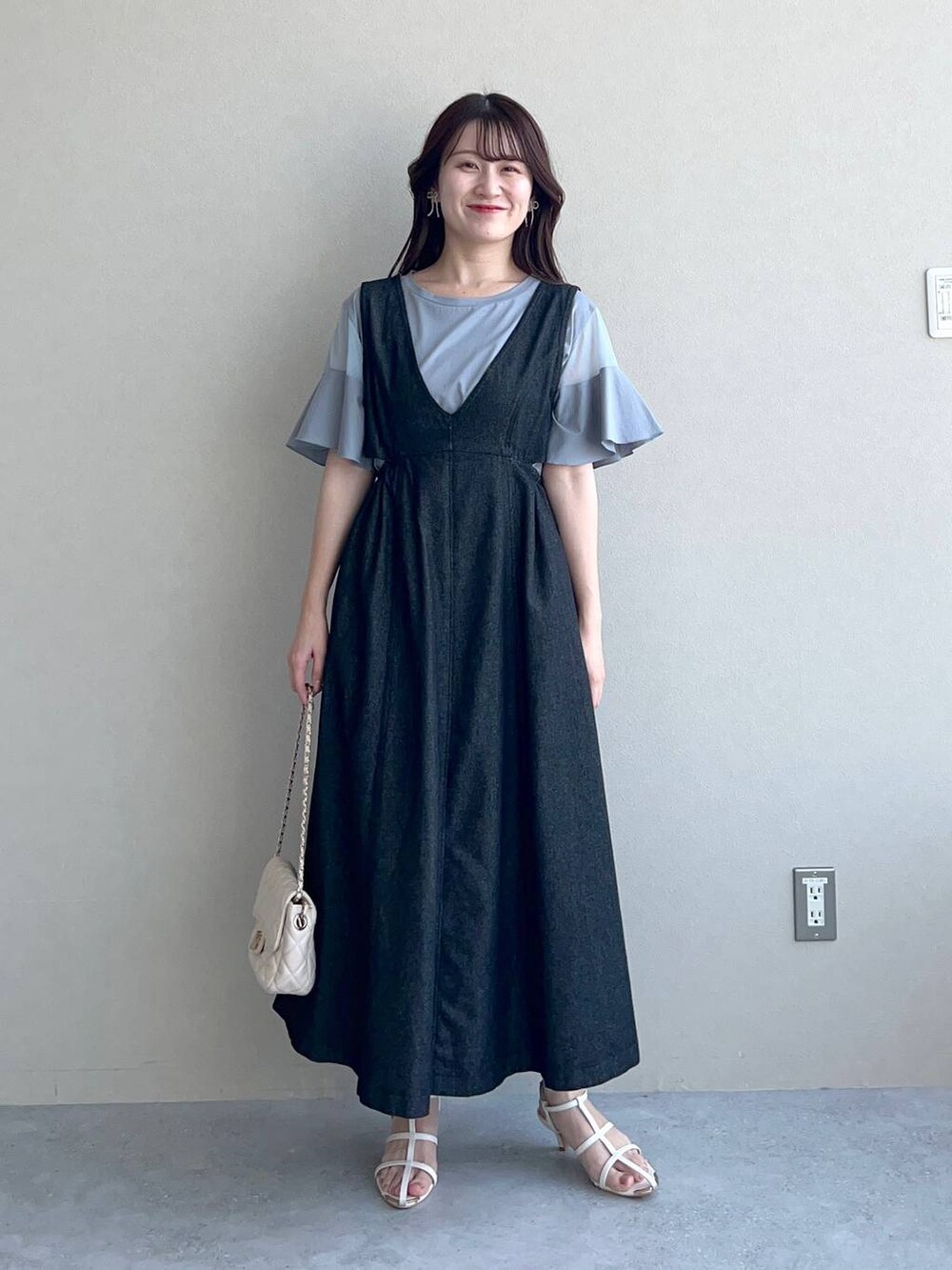 ブルー系のTシャツ/カットソー、ホワイト系のショルダーバッグ、ブラック系のジャンパースカートを着用したレディースの夏コーディネートの2枚目の写真