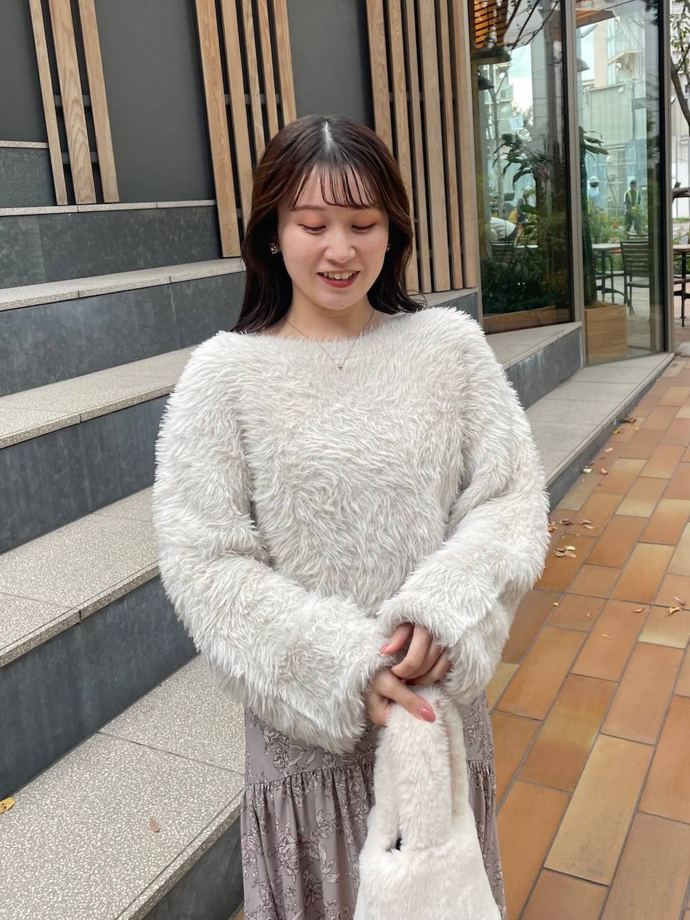 ホワイト系のハンドバッグ、ベージュ系のスカート、ベージュ系のニット/セーターを着用したレディースの冬コーディネートの2枚目の写真