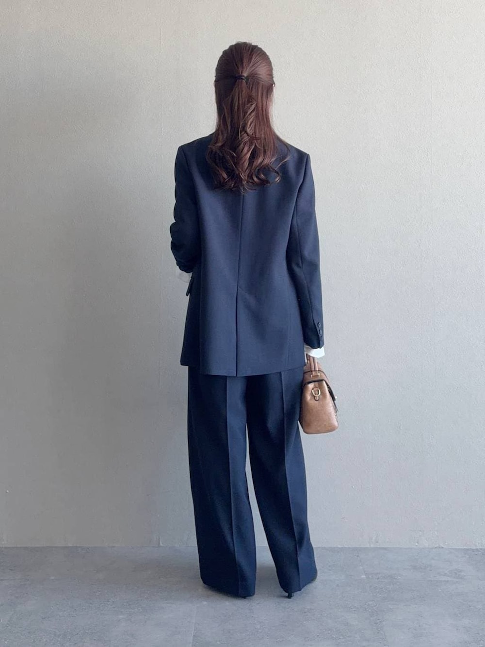 ブラック系のショルダーバッグ、ブルー系のテーラードジャケット、ブルー系のその他パンツを着用したレディースの冬コーディネートの2枚目の写真