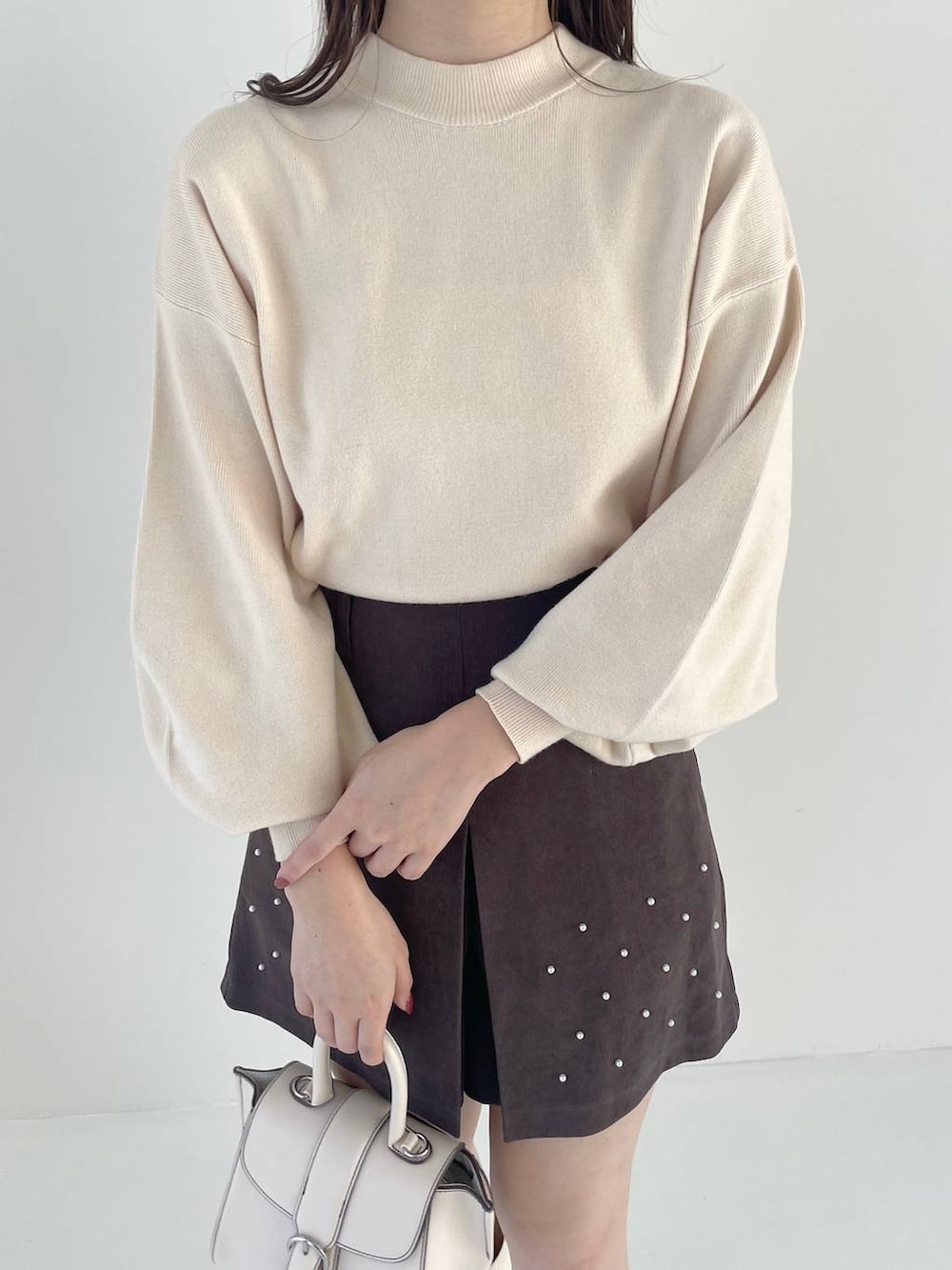 ホワイト系のハンドバッグ、ホワイト系のブーツ、ホワイト系のニット/セーターを着用したレディースの秋コーディネートの7枚目の写真