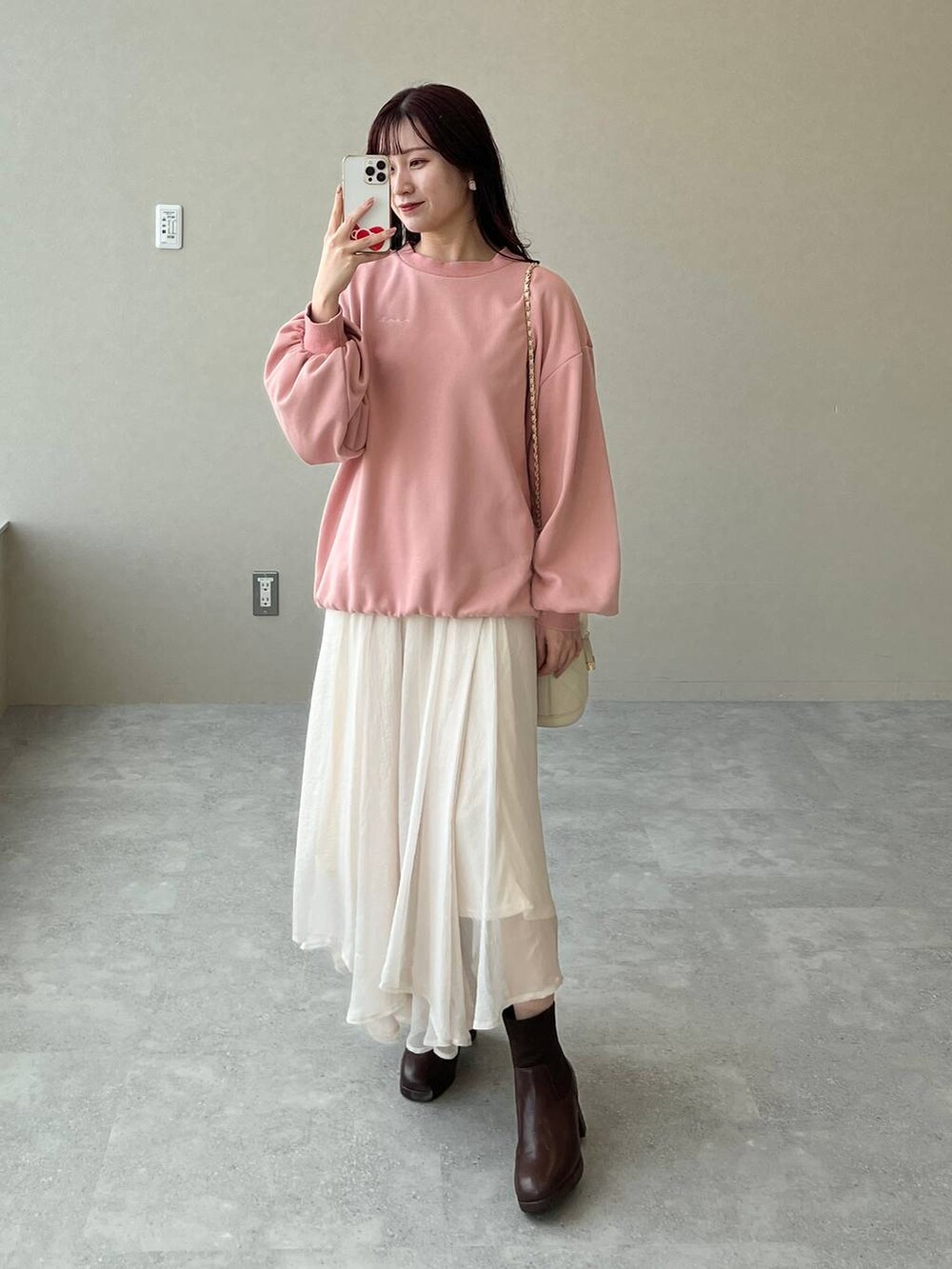 ブラウン系のブーツ、ピンク系のスウェット、ホワイト系のショルダーバッグを着用したレディースの秋コーディネートの5枚目の写真