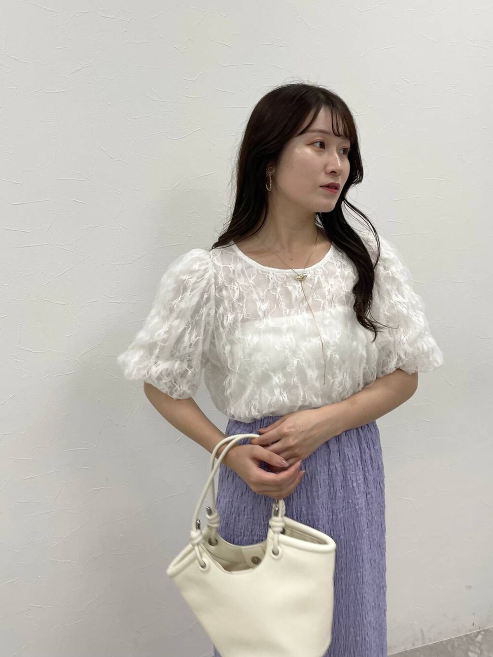 ホワイト系のハンドバッグ、パープル系のスカート、ホワイト系のサンダルを着用したレディースの夏コーディネートの3枚目の写真