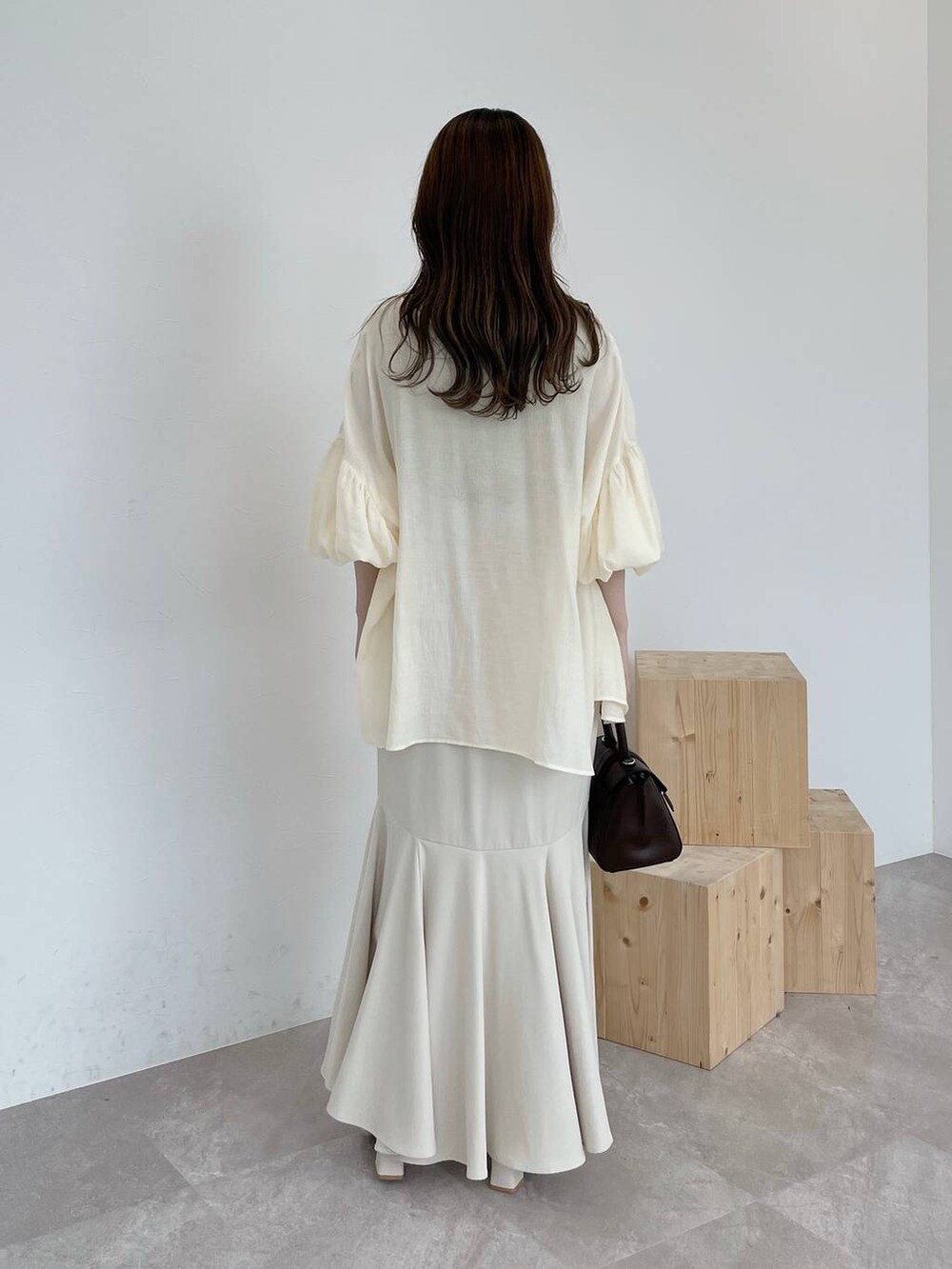 イエロー系のニット/セーター、ブラウン系のハンドバッグ、ホワイト系のシャツ/ブラウスを着用したレディースの夏コーディネートの3枚目の写真