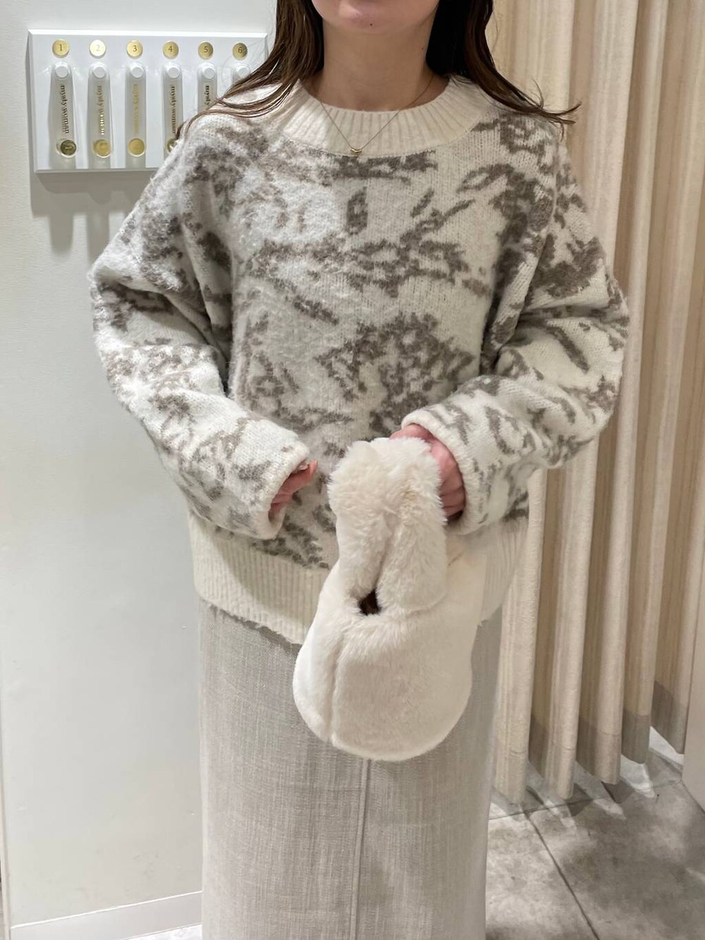 ホワイト系のブーツ、ホワイト系のハンドバッグ、ホワイト系のスカートを着用したレディースの冬コーディネートの6枚目の写真