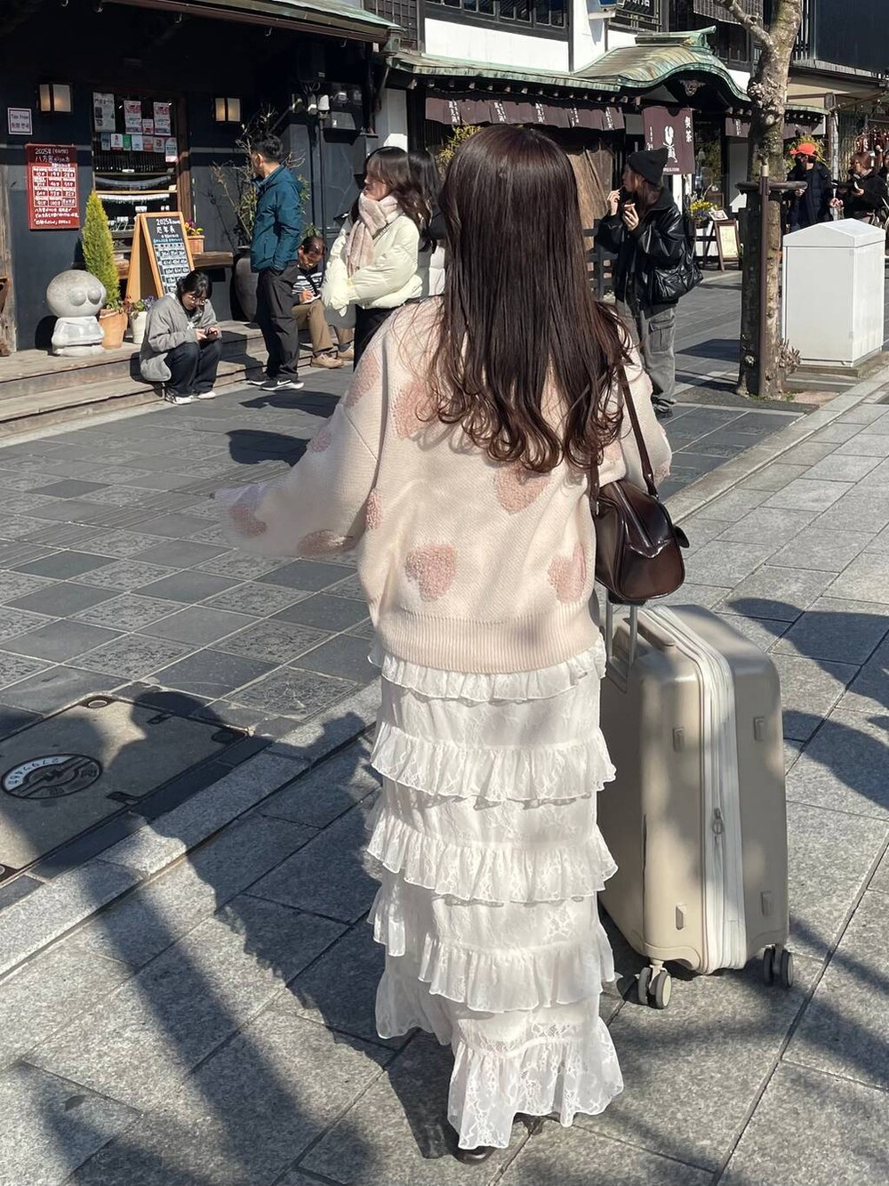 ブラウン系のハンドバッグ、ホワイト系のニット/セーター、ホワイト系のスカートを着用したレディースの冬コーディネートの2枚目の写真