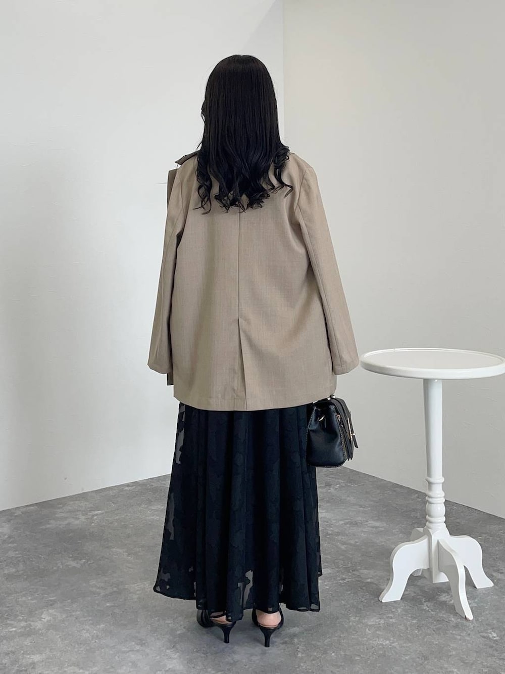 ベージュ系のテーラードジャケット、ブラック系のワンピース、ブラック系のパンプスを着用したレディースの秋コーディネートの2枚目の写真