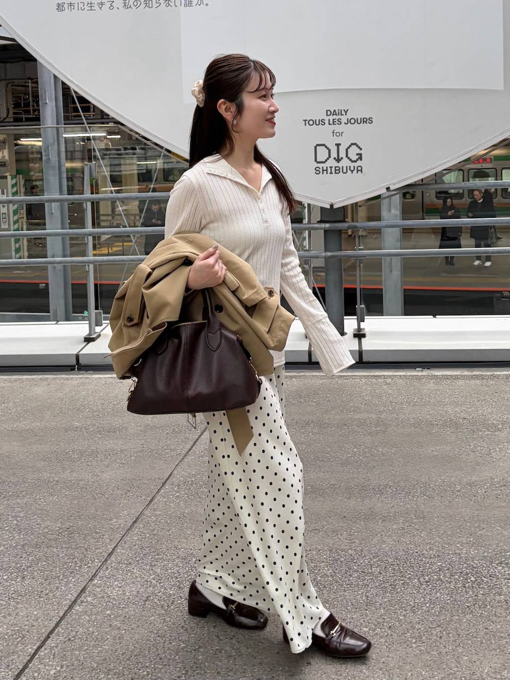 ホワイト系のスカート、ブラウン系のボストンバッグ、ベージュ系のトレンチコートを着用したレディースの冬コーディネートの6枚目の写真