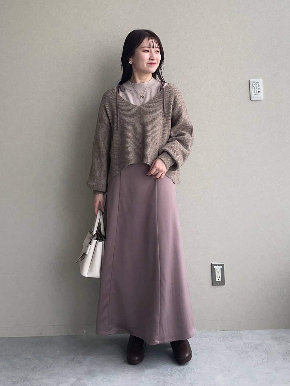 ブラウン系のブーツ、ベージュ系のニット/セーター、ホワイト系のブルゾンを着用したレディースの冬コーディネートの3枚目の写真