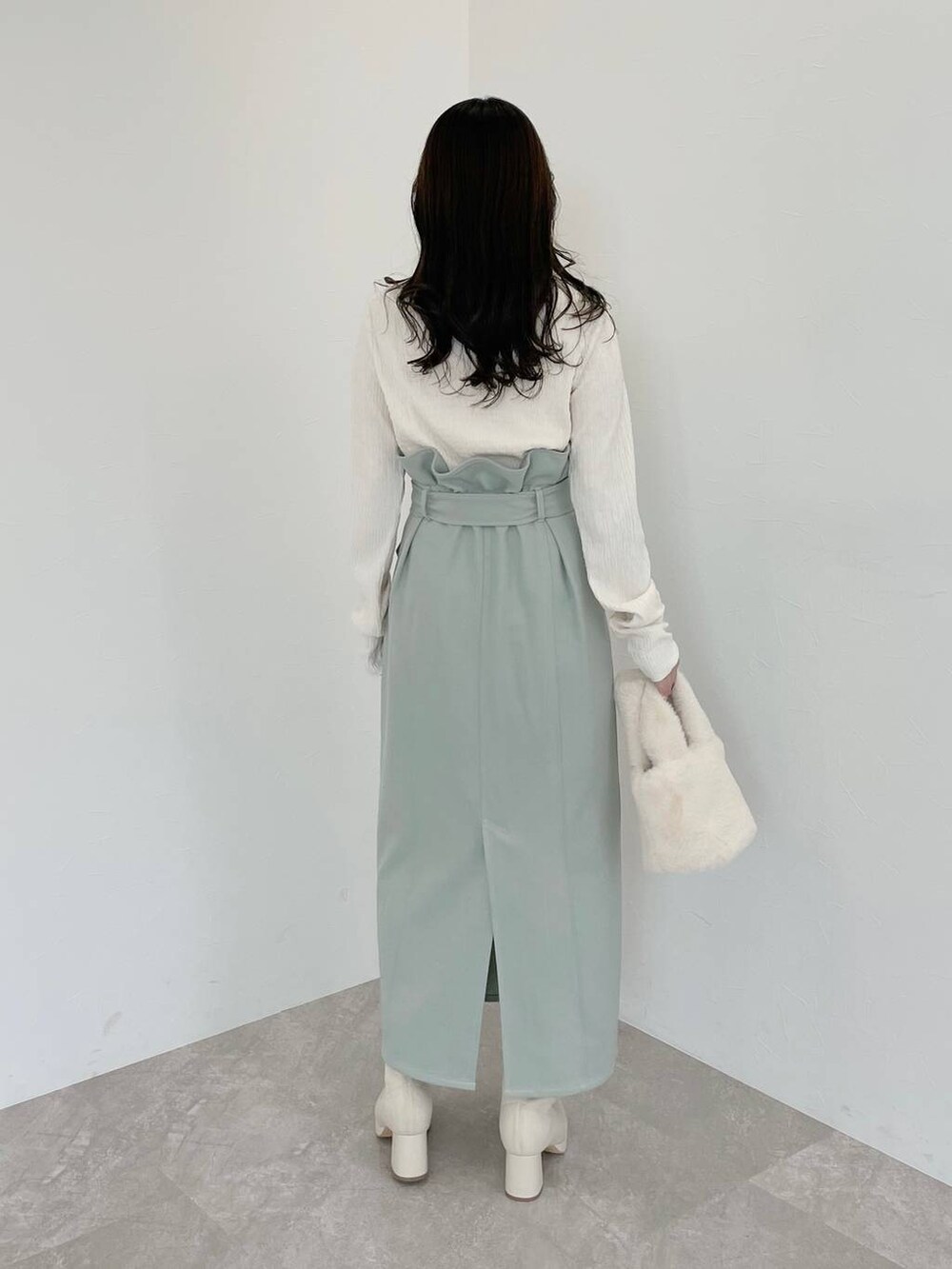 ホワイト系のブーツ、ホワイト系のハンドバッグ、グリーン系のスカートを着用したレディースの冬コーディネートの6枚目の写真