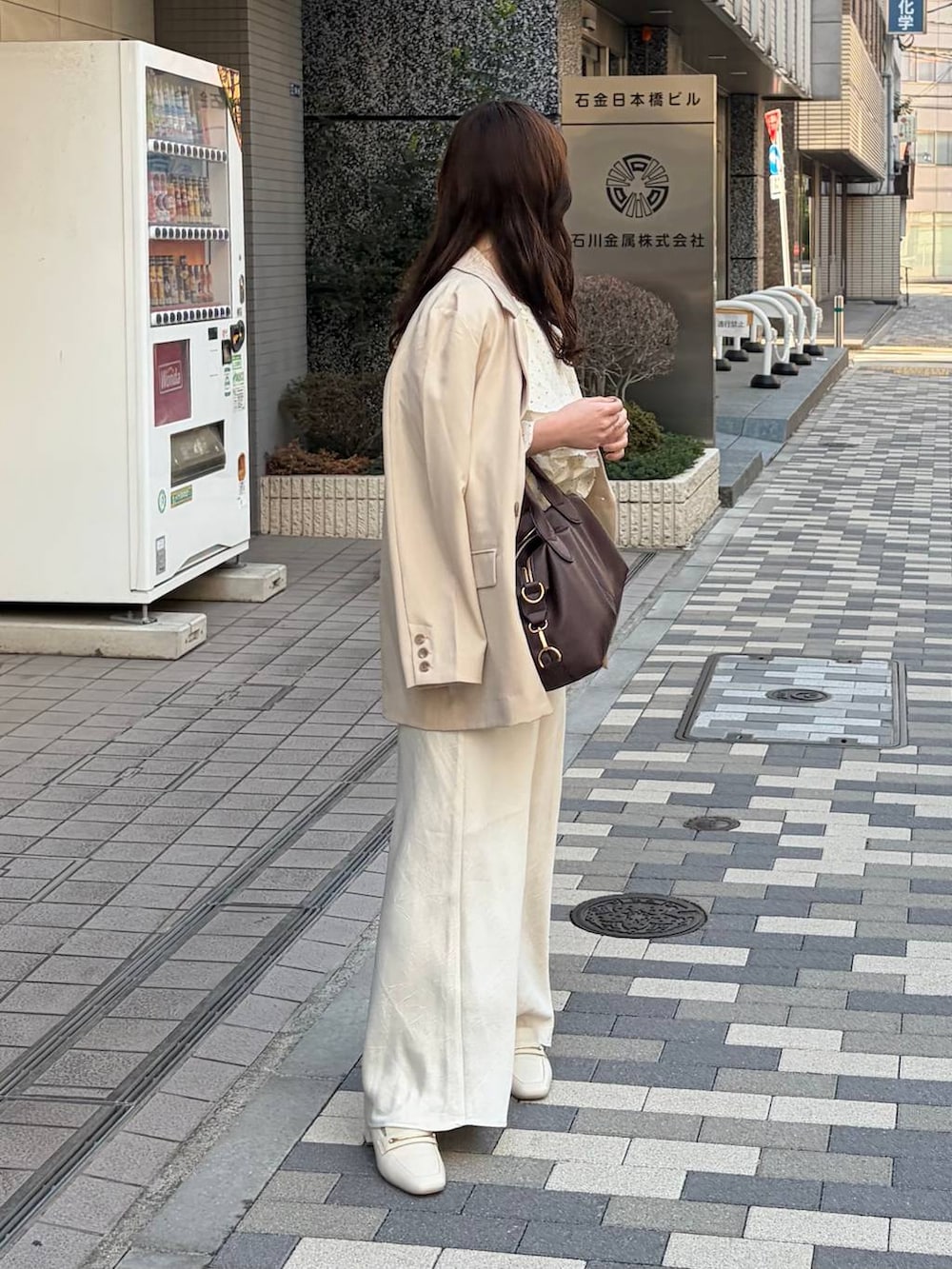 ホワイト系のスカート、ブラウン系のボストンバッグ、ベージュ系のテーラードジャケットを着用したレディースの春コーディネートの3枚目の写真