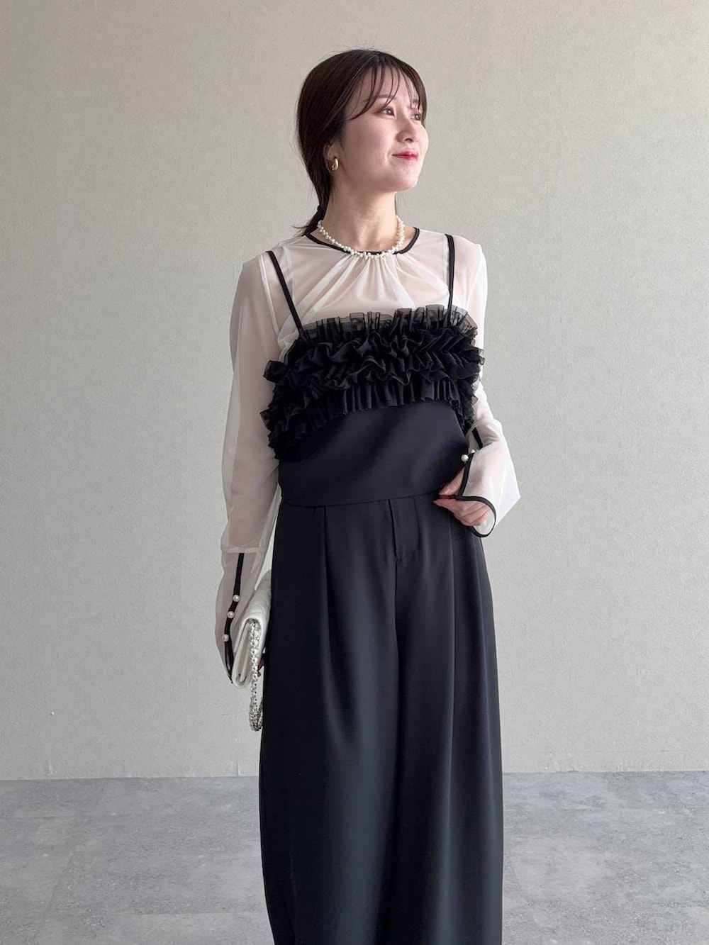 ブラック系のサンダル、ホワイト系のショルダーバッグ、ブラック系のパンツドレスを着用したレディースの春コーディネートの3枚目の写真