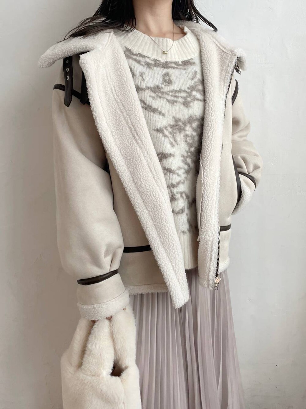 ホワイト系のブーツ、ホワイト系のハンドバッグ、ベージュ系のスカートを着用したレディースの秋コーディネートの3枚目の写真