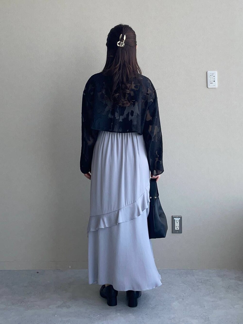 ブラック系のワンピース、ブラック系のショルダーバッグ、グレー系のスカートを着用したレディースの春コーディネートの2枚目の写真