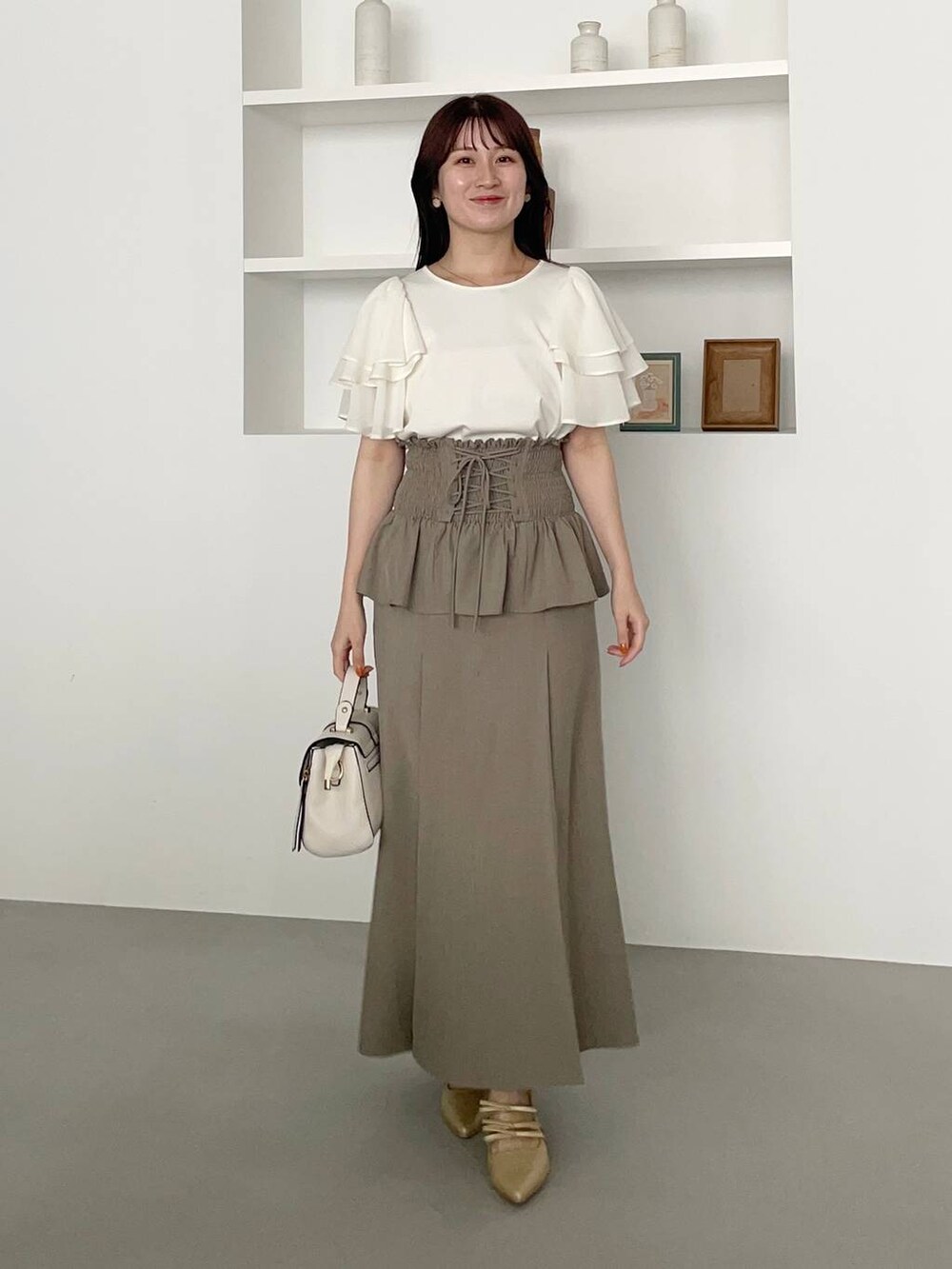 ゴールド系のパンプス、ホワイト系のショルダーバッグ、ホワイト系のTシャツ/カットソーを着用したレディースの春コーディネートの2枚目の写真