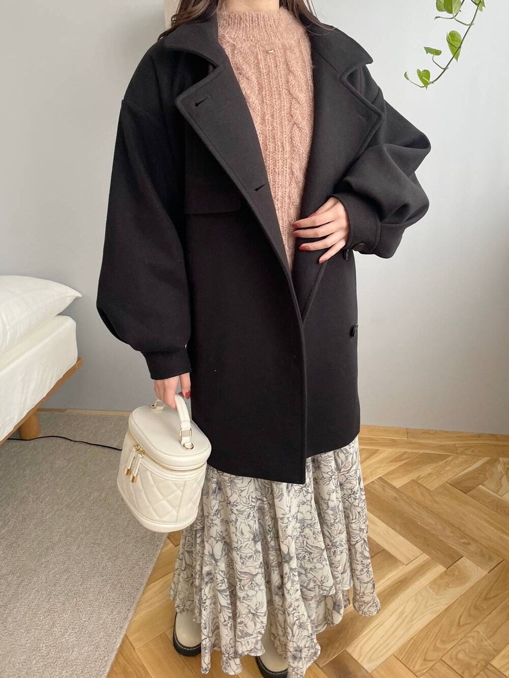 ブラック系のチェスターコート、ホワイト系のブーツ、ベージュ系のスカートを着用したレディースの秋コーディネートの3枚目の写真