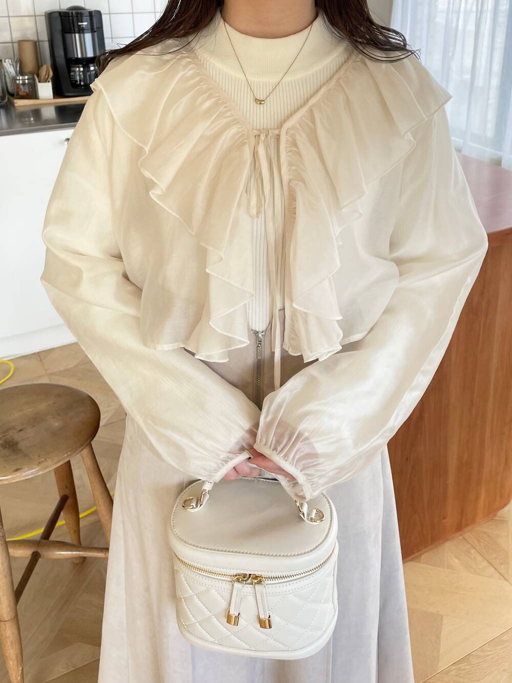 ホワイト系のショルダーバッグ、ブラウン系のブーツ、ベージュ系のブルゾンを着用したレディースの冬コーディネートの7枚目の写真