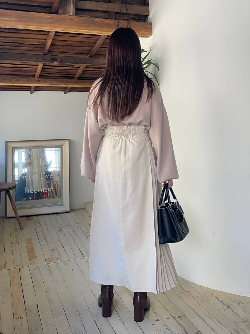 グレー系のピーコート、ブラウン系のブーツ、ホワイト系のスカートを着用したレディースの冬コーディネートの4枚目の写真