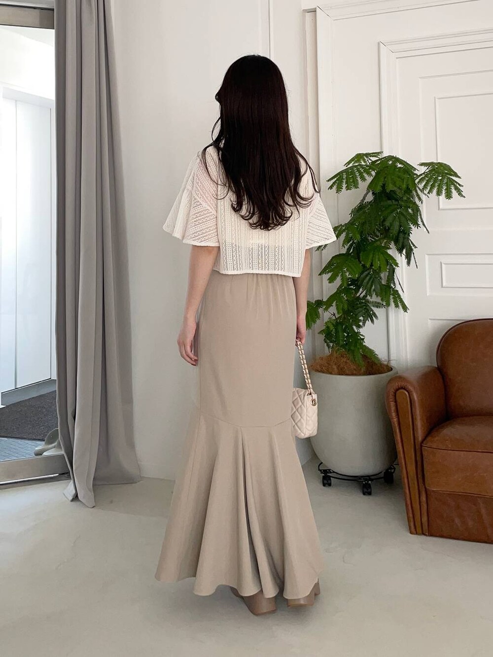 ベージュ系のサンダル、ホワイト系のカーディガン/ボレロ、ホワイト系のショルダーバッグを着用したレディースの夏コーディネートの2枚目の写真