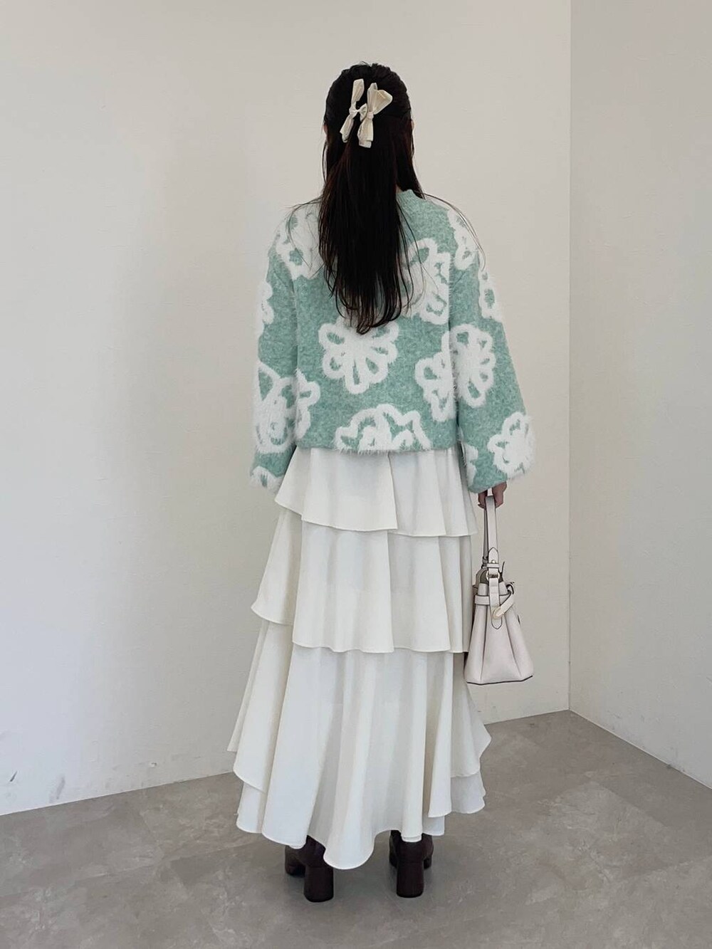 ホワイト系のショルダーバッグ、ブラウン系のブーツ、ホワイト系のスカートを着用したレディースの冬コーディネートの2枚目の写真