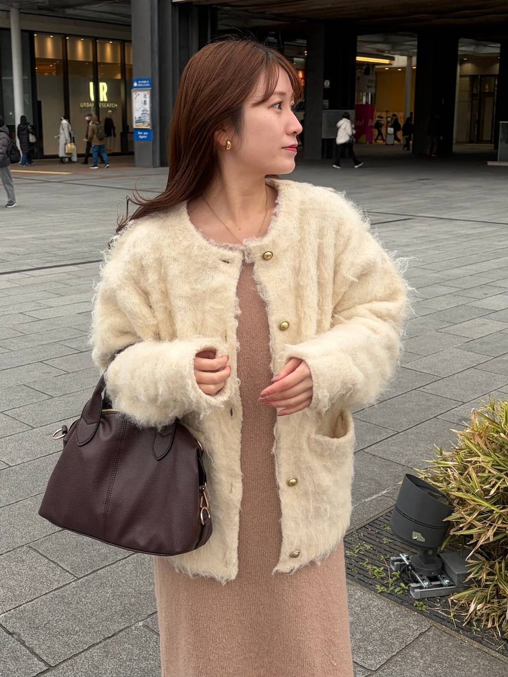 ブラウン系のボストンバッグ、ピンク系のワンピース、ホワイト系のカーディガン/ボレロを着用したレディースの冬コーディネートの3枚目の写真