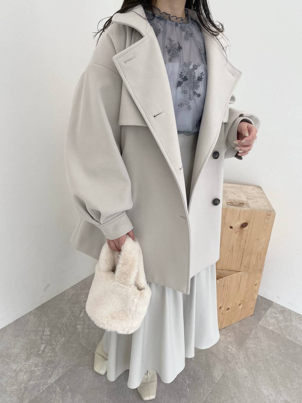 ホワイト系のチェスターコート、ホワイト系のブーツ、ブルー系のシャツ/ブラウスを着用したレディースの秋コーディネートの3枚目の写真