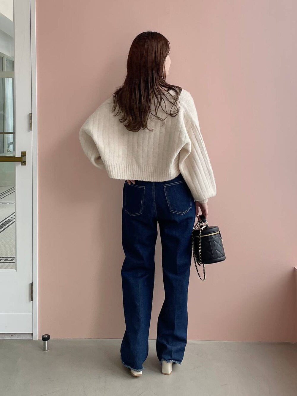 ブルー系のデニムパンツ、ホワイト系のパンプス、ブラック系のショルダーバッグを着用したレディースの秋コーディネートの2枚目の写真