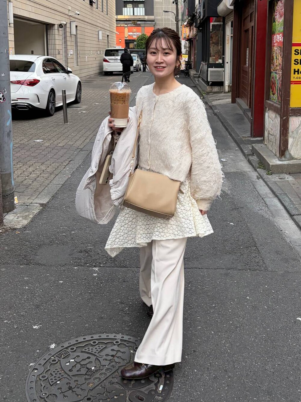 ゴールド系のボストンバッグ、ホワイト系のスカート、ホワイト系のブルゾンを着用したレディースの冬コーディネートの2枚目の写真