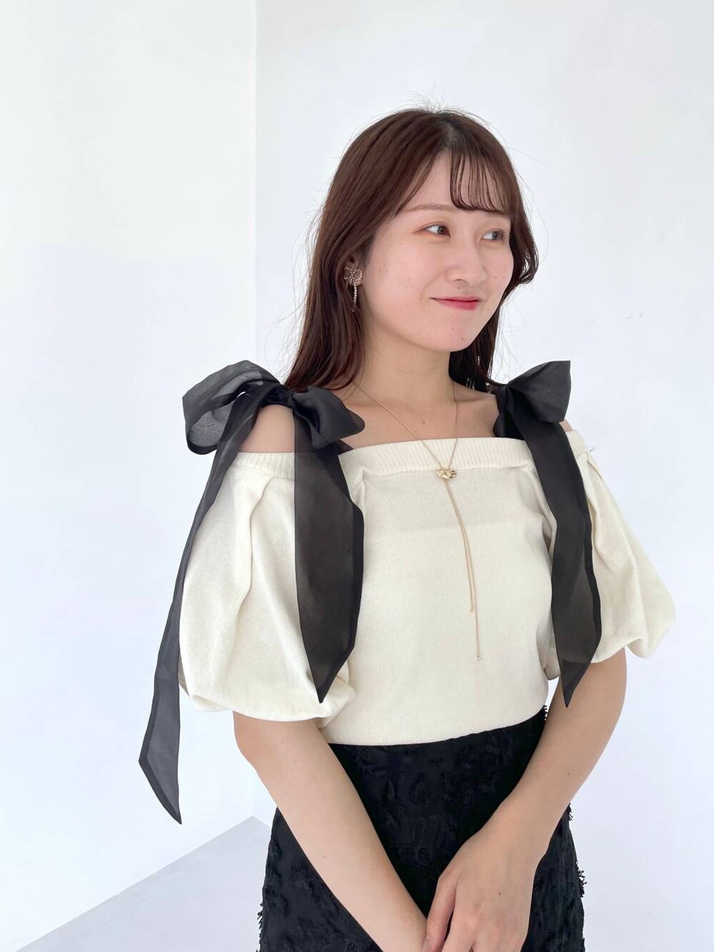 ホワイト系のニット/セーター、ブラック系のショルダーバッグ、ホワイト系のサンダルを着用したレディースの夏コーディネートの3枚目の写真