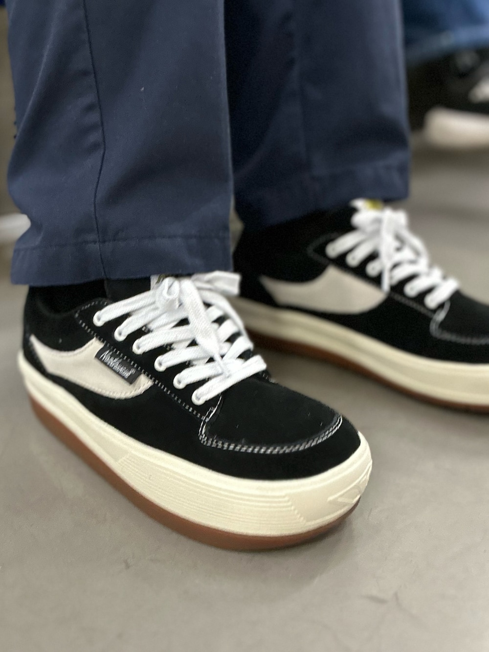 ブラック系のスニーカー、ブルー系のチノパンツ、グリーン系のダウンベストを着用したメンズの冬コーディネートの2枚目の写真