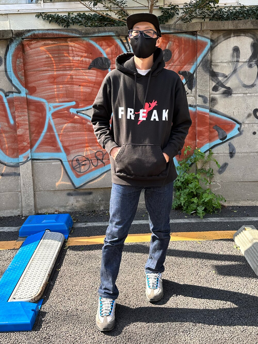 ブルー系のスニーカー、ブルー系のデニムパンツ、ブラック系のパーカーを着用したメンズの春コーディネートの3枚目の写真