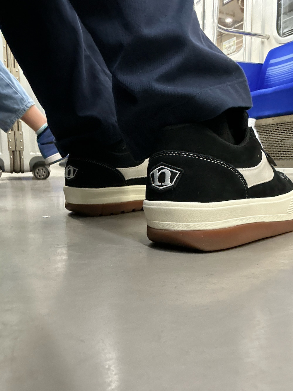 ブラック系のスニーカー、ブルー系のチノパンツ、グリーン系のダウンベストを着用したメンズの冬コーディネートの3枚目の写真