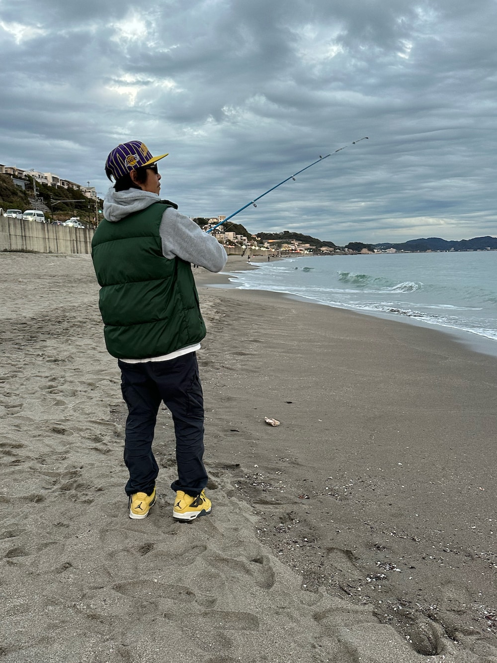 イエロー系のスニーカー、ブルー系のカーゴパンツ、グレー系のパーカーを着用したメンズの秋コーディネートの2枚目の写真