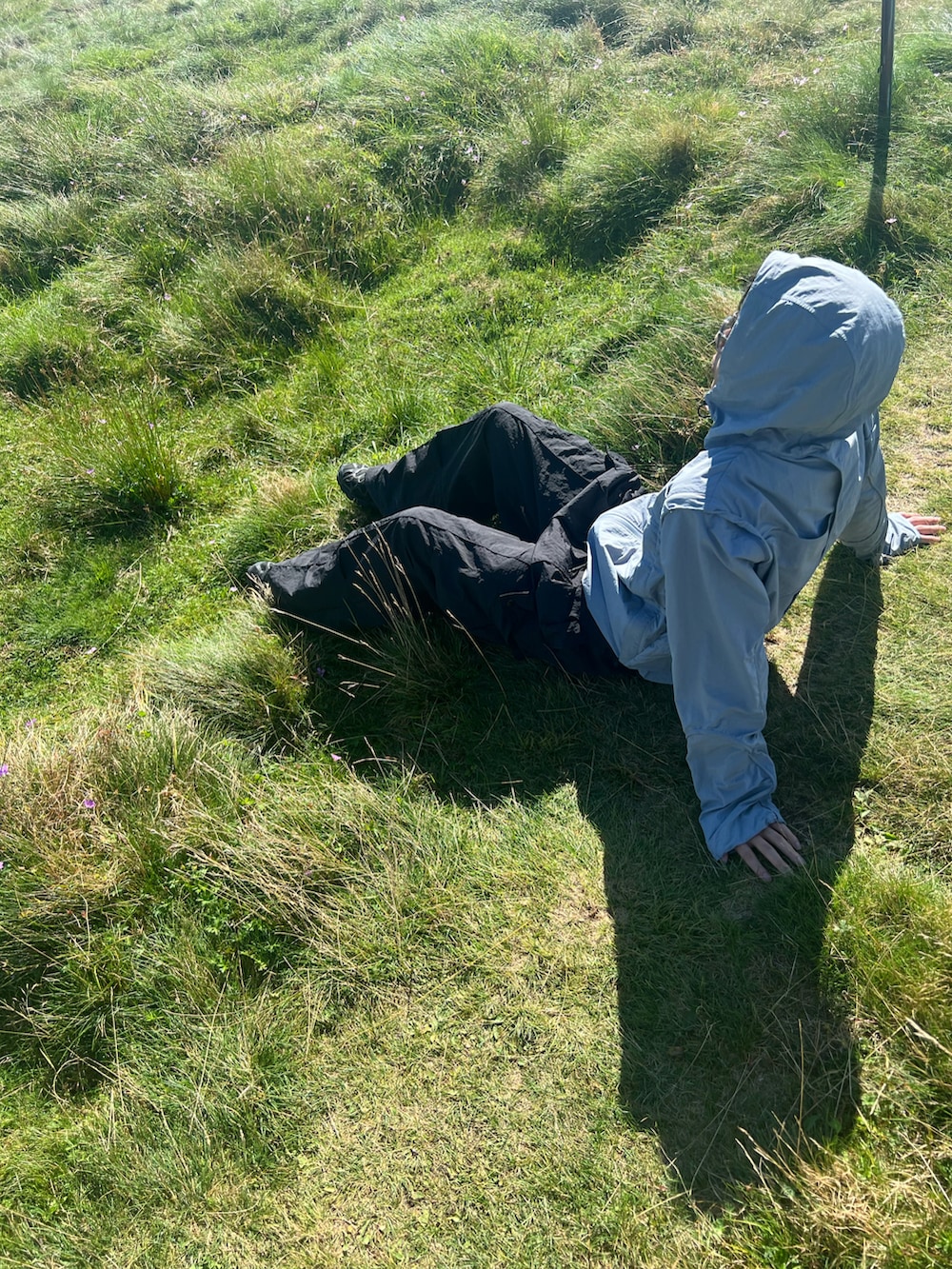 ブラック系のカーゴパンツ、ブルー系のナイロンジャケット、ブラック系のスニーカーを着用したメンズの秋コーディネートの2枚目の写真