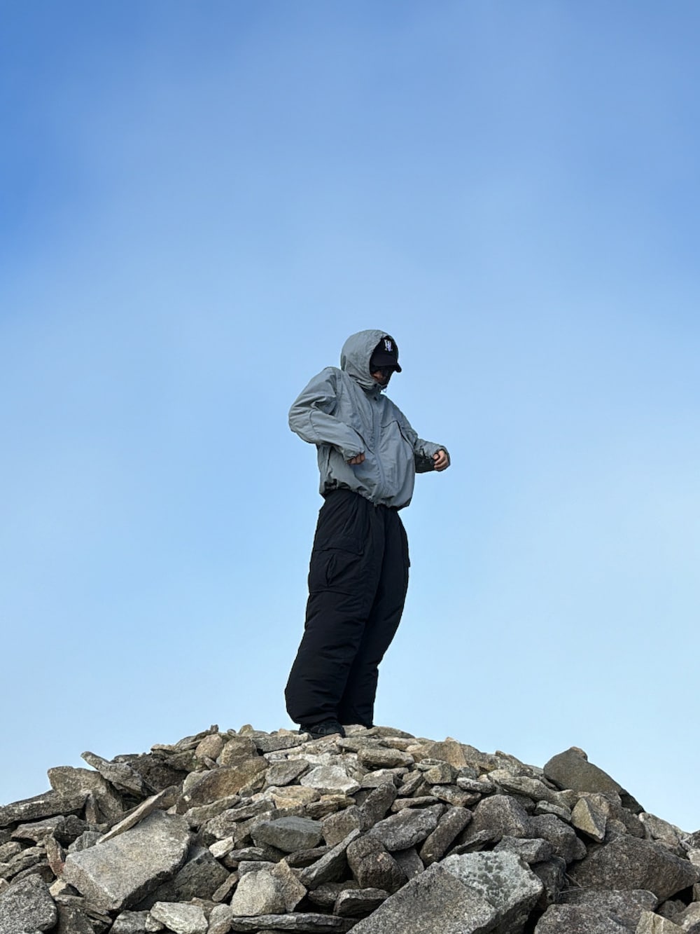 ブラック系のカーゴパンツ、ブルー系のナイロンジャケット、ブラック系のスニーカーを着用したメンズの秋コーディネートの3枚目の写真