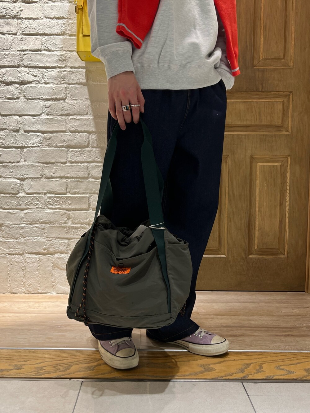 グレー系のスウェット、レッド系のカーディガン/ボレロ、ブルー系のデニムパンツを着用したメンズの春コーディネートの3枚目の写真