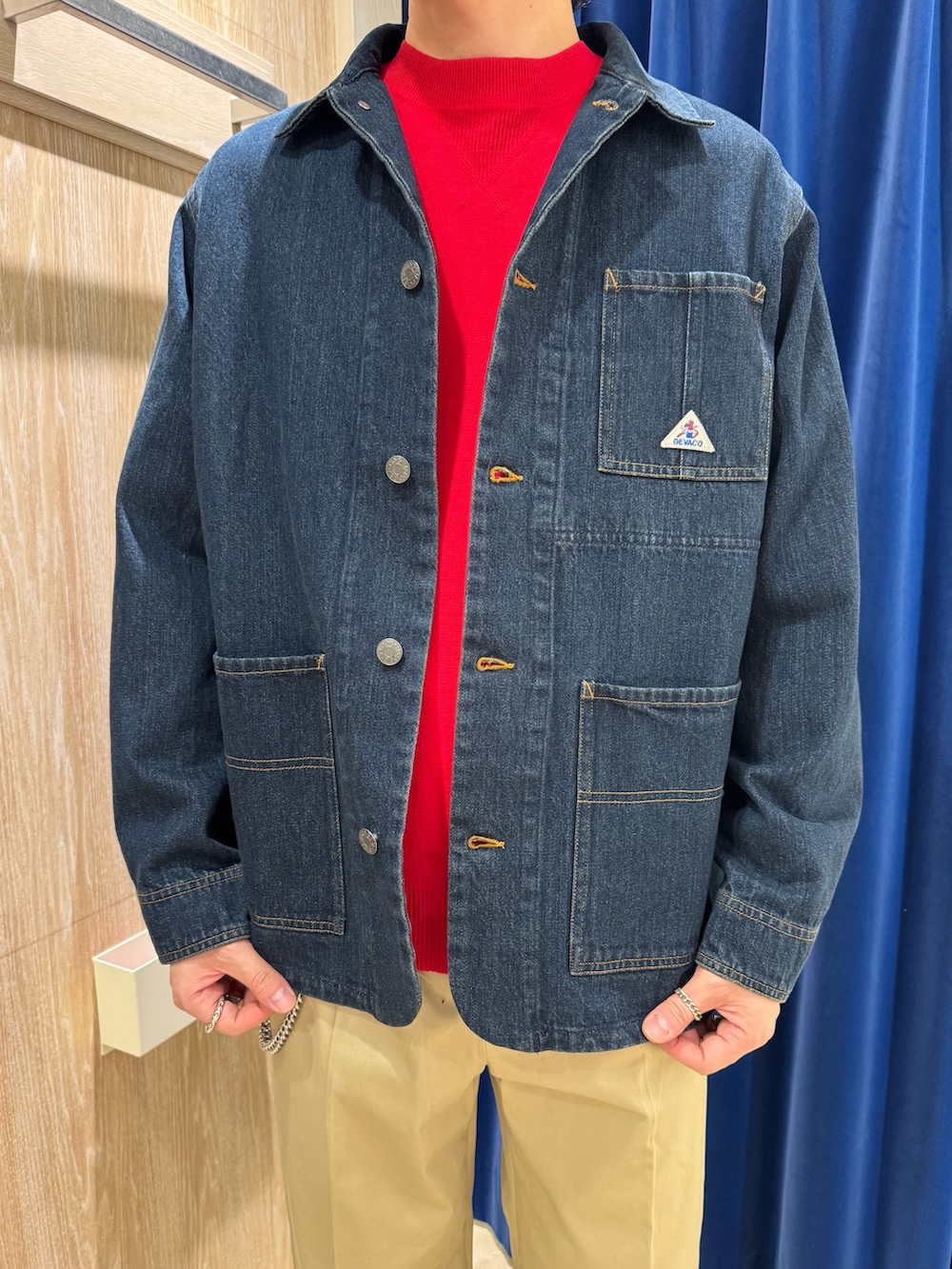 ブルー系のカバーオール、レッド系のスウェット、ベージュ系のチノパンツを着用したメンズの春コーディネートの2枚目の写真