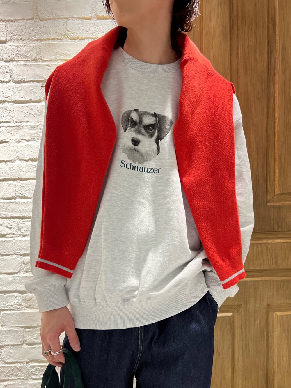 グレー系のスウェット、レッド系のカーディガン/ボレロ、ブルー系のデニムパンツを着用したメンズの春コーディネートの2枚目の写真