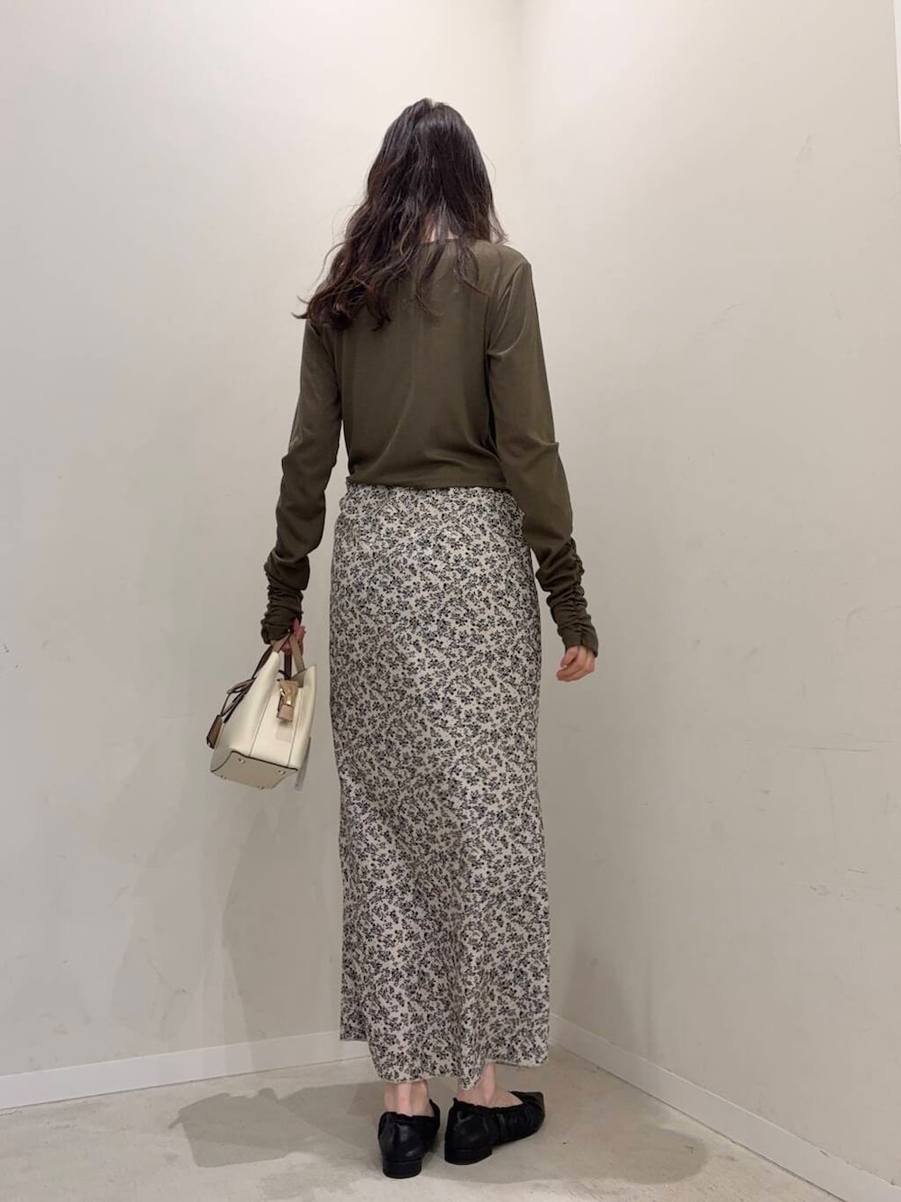 ホワイト系のハンドバッグ、ブラック系のバレエシューズ、グリーン系のTシャツ/カットソーを着用したレディースの春コーディネートの2枚目の写真