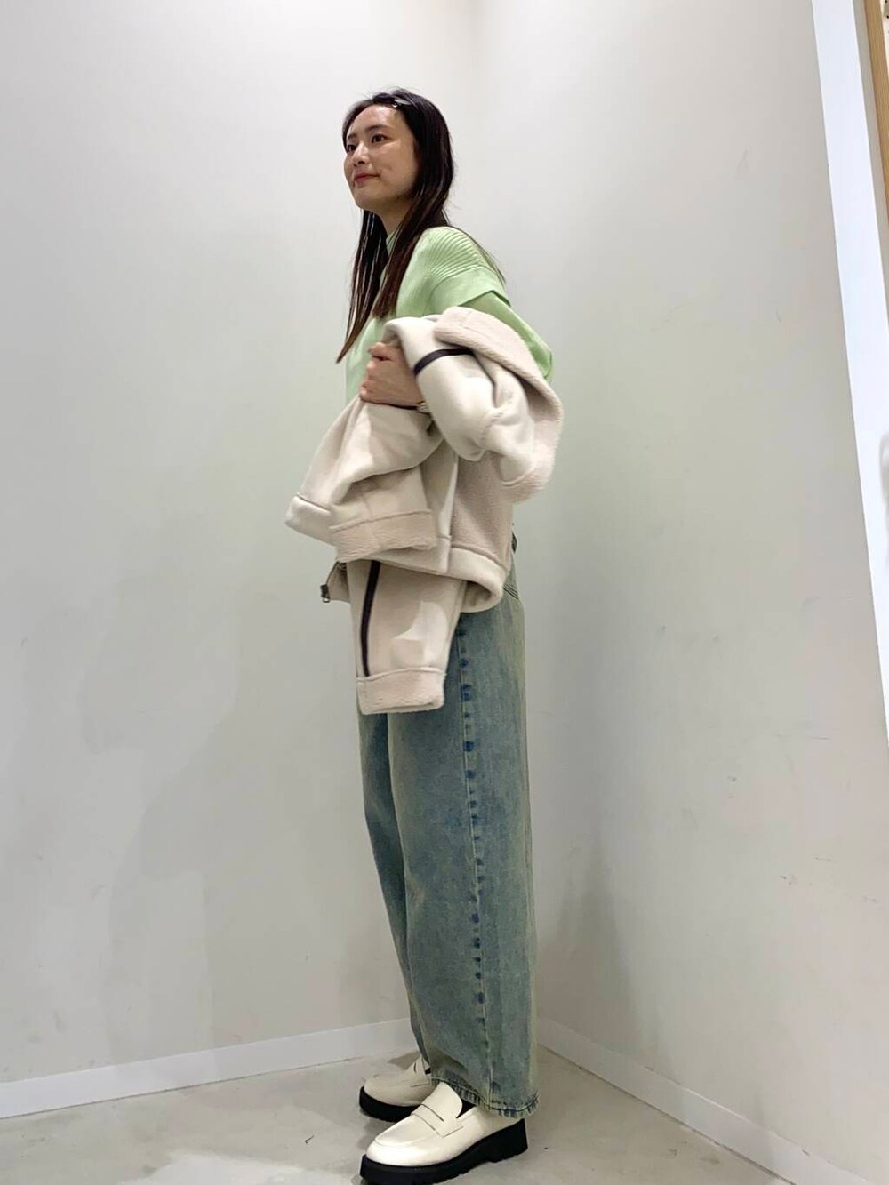 ブラック系のショルダーバッグ、ブルー系のデニムパンツ、ホワイト系のローファーを着用したレディースの冬コーディネートの2枚目の写真