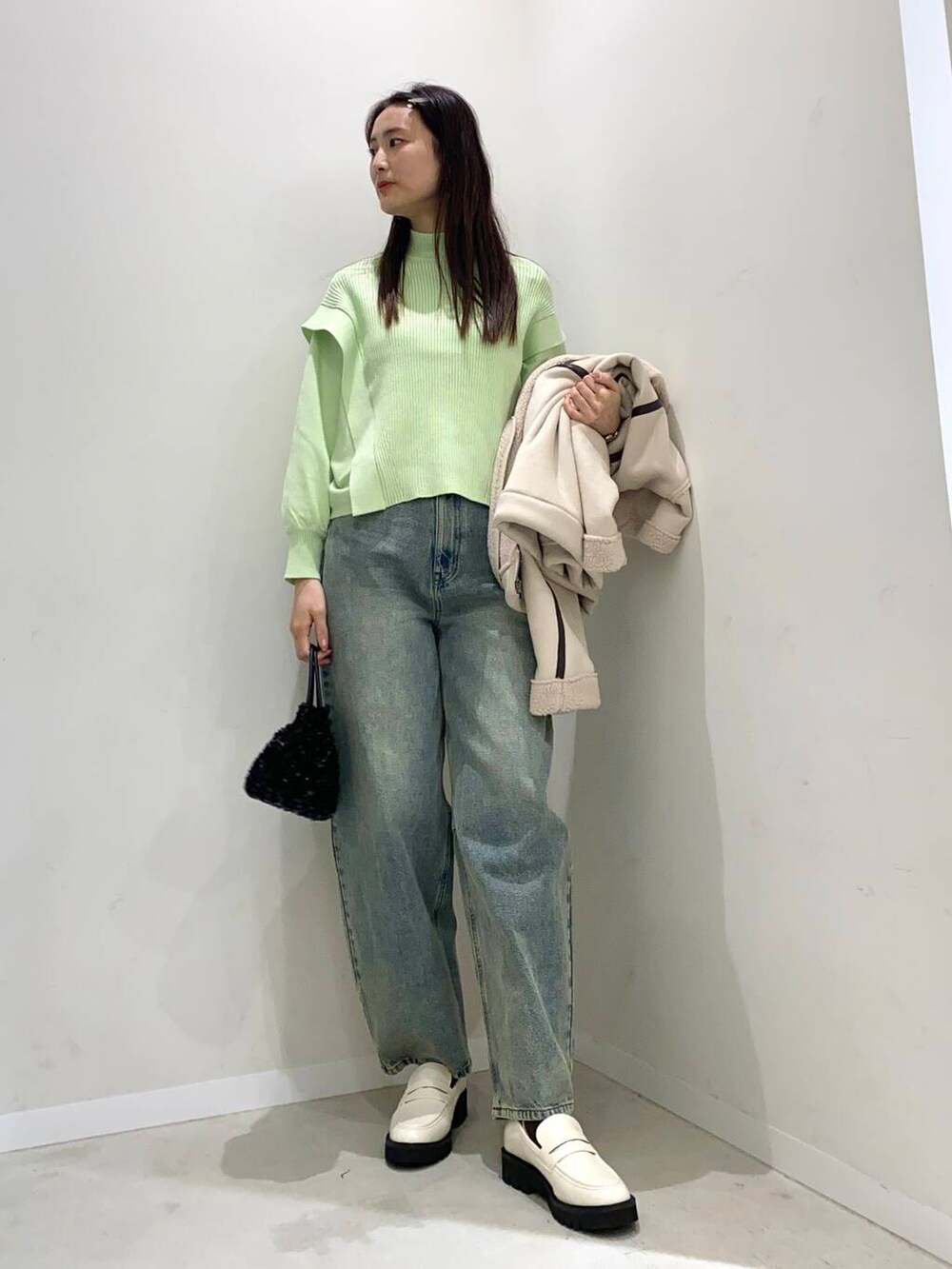 ブラック系のショルダーバッグ、ブルー系のデニムパンツ、ホワイト系のローファーを着用したレディースの冬コーディネートの4枚目の写真