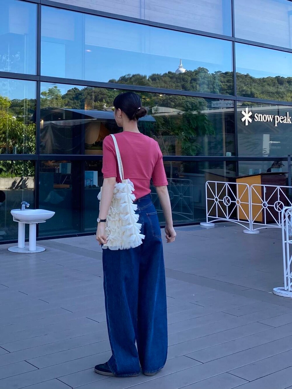 ブルー系のデニムパンツ、ホワイト系のトートバッグ、ブラック系のスニーカーを着用したレディースの夏コーディネートの2枚目の写真