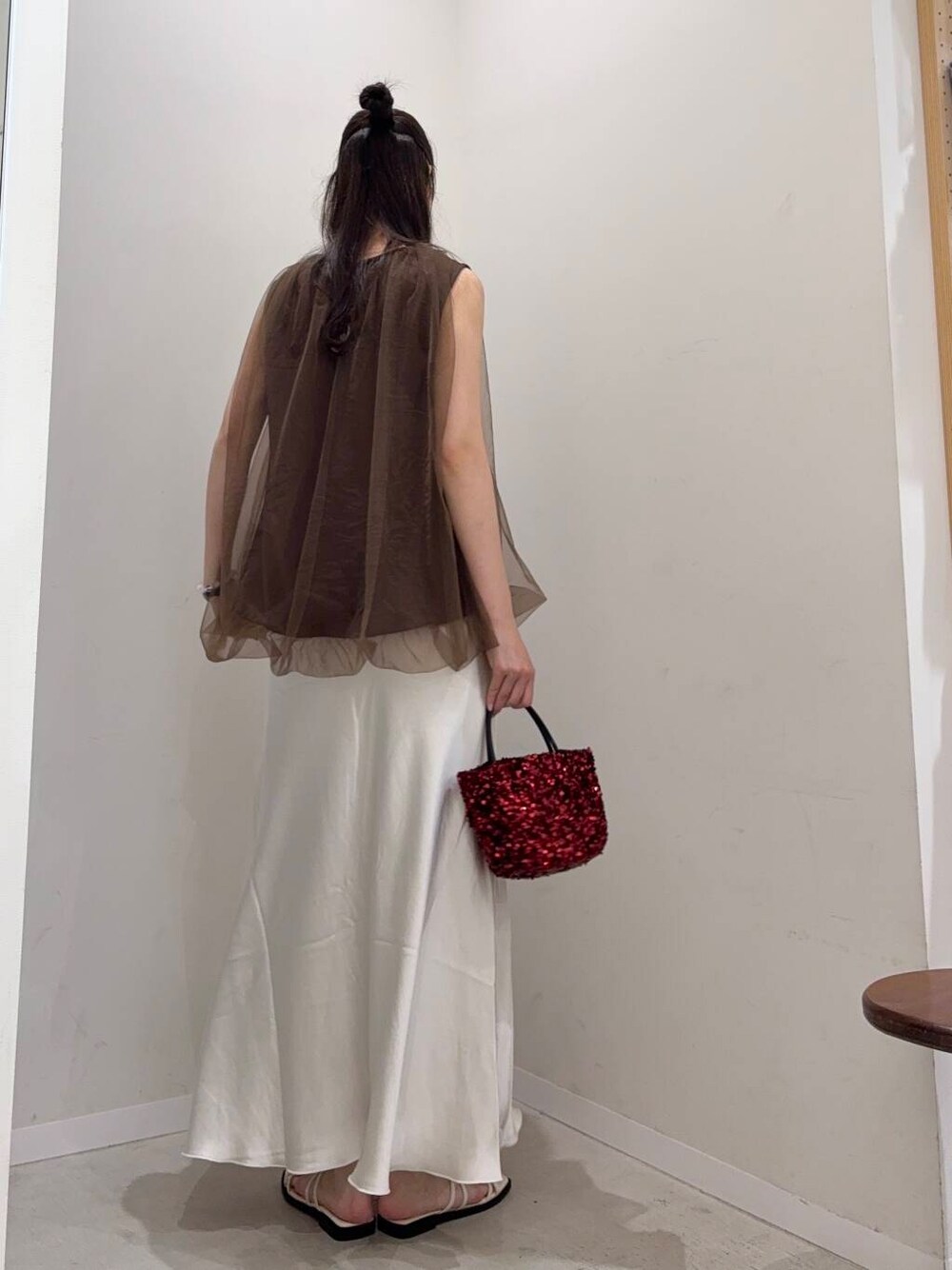 レッド系のショルダーバッグ、ホワイト系のスカート、ホワイト系のタンクトップを着用したレディースの夏コーディネートの2枚目の写真