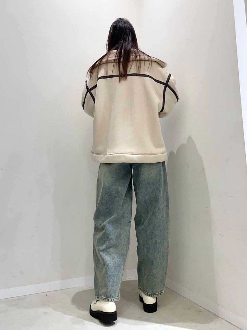 ブラック系のショルダーバッグ、ブルー系のデニムパンツ、ホワイト系のローファーを着用したレディースの冬コーディネートの3枚目の写真