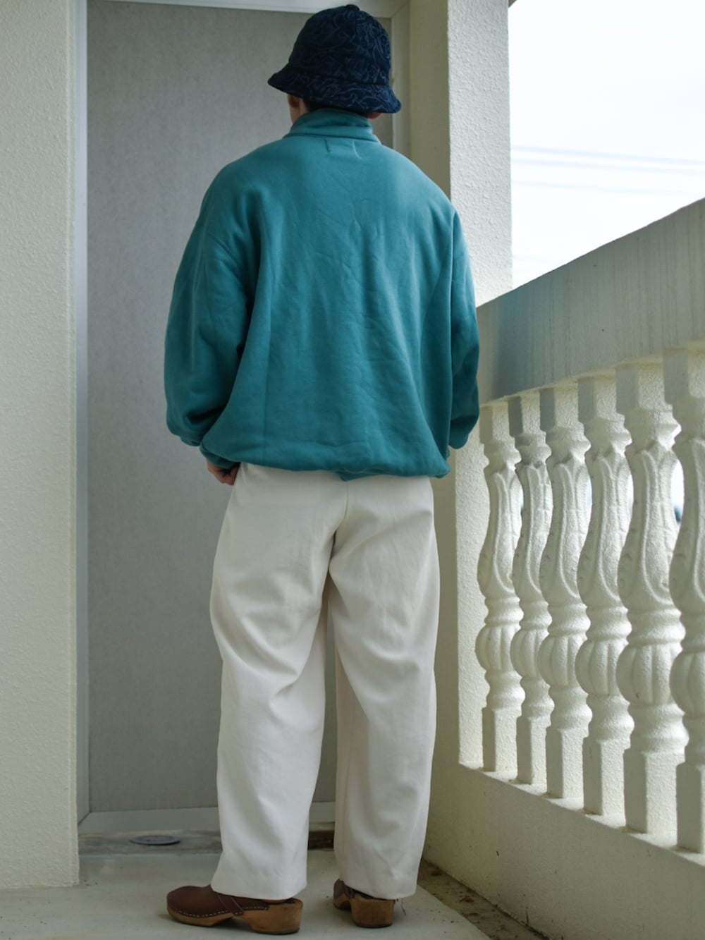 ブラウン系のサンダル、ホワイト系のスラックス、ブルー系のスウェットを着用したメンズの冬コーディネートの2枚目の写真